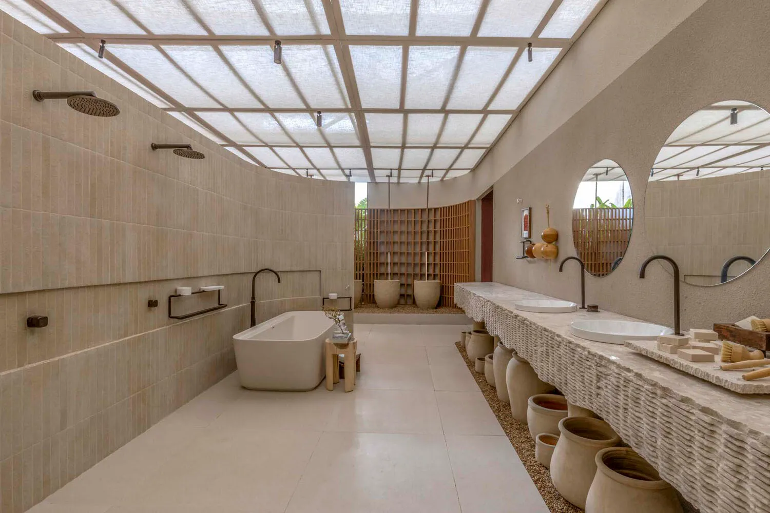 A modern bathroom featuring concrete tiles, a freestanding bathtub, and potted plants lined along the walls.