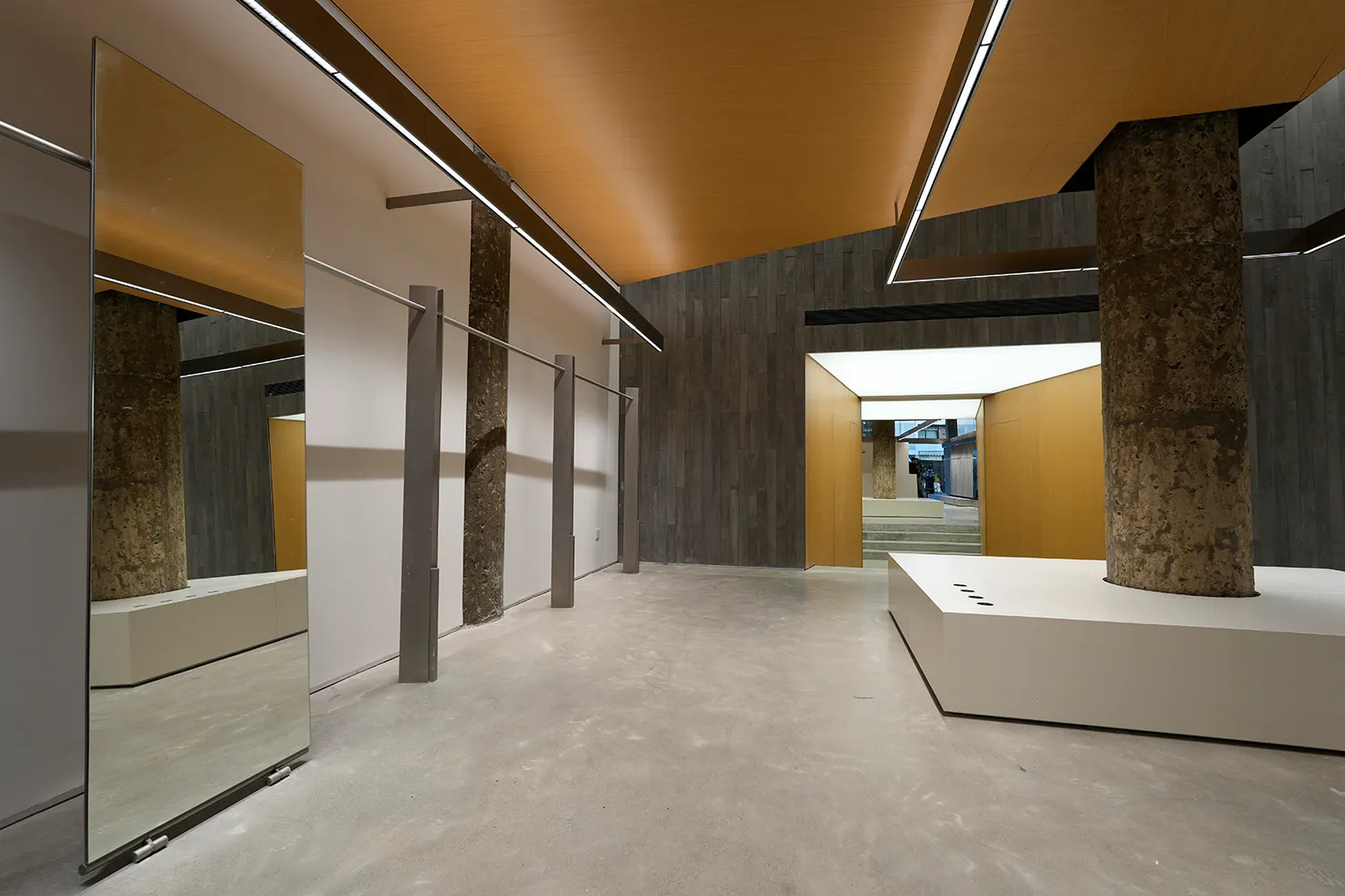 A minimalist industrial installation featuring concrete walls and floors in a space with concrete pillars.