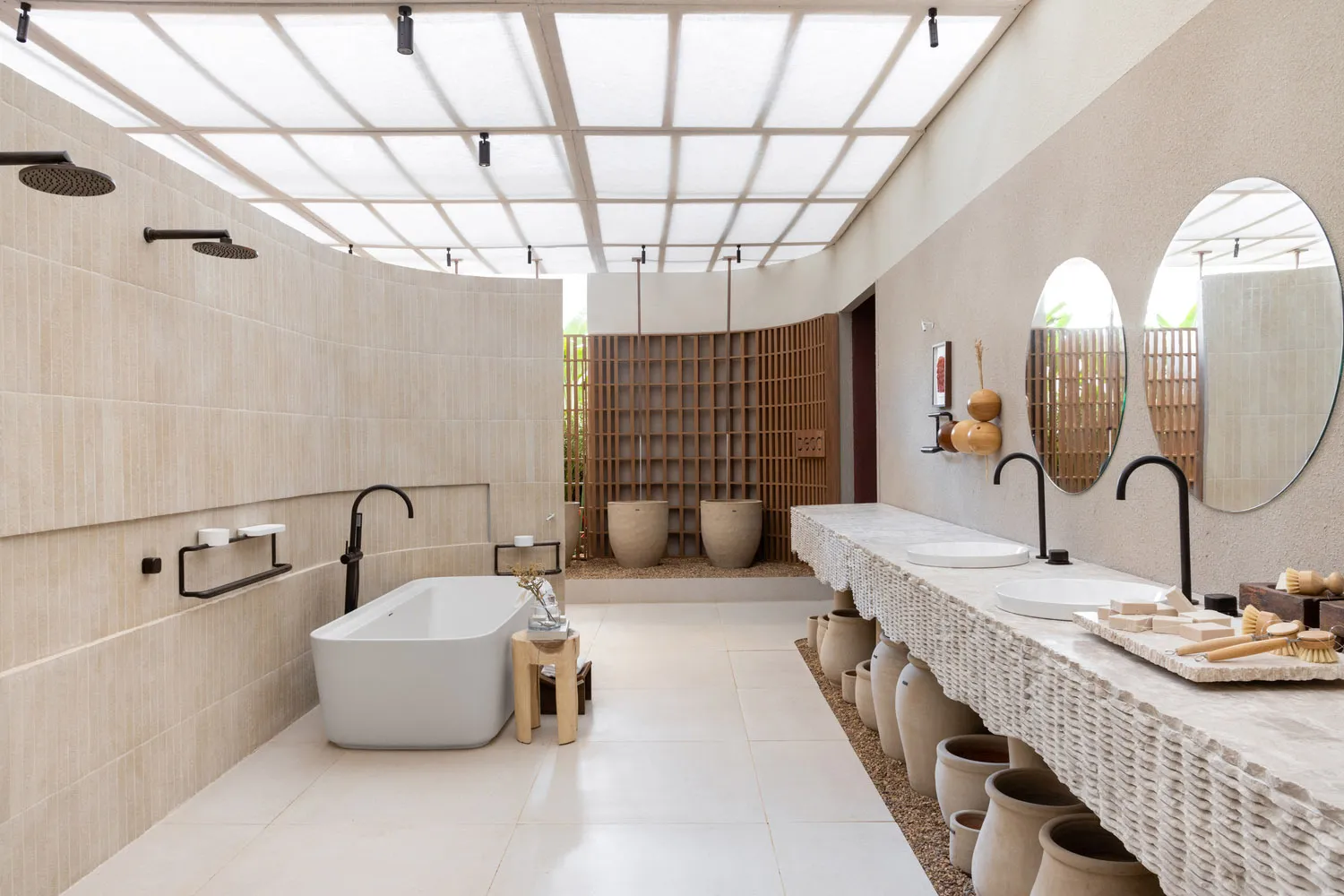 Modern minimalist bathroom featuring stone tiles, a freestanding bathtub, and a double sink vanity.