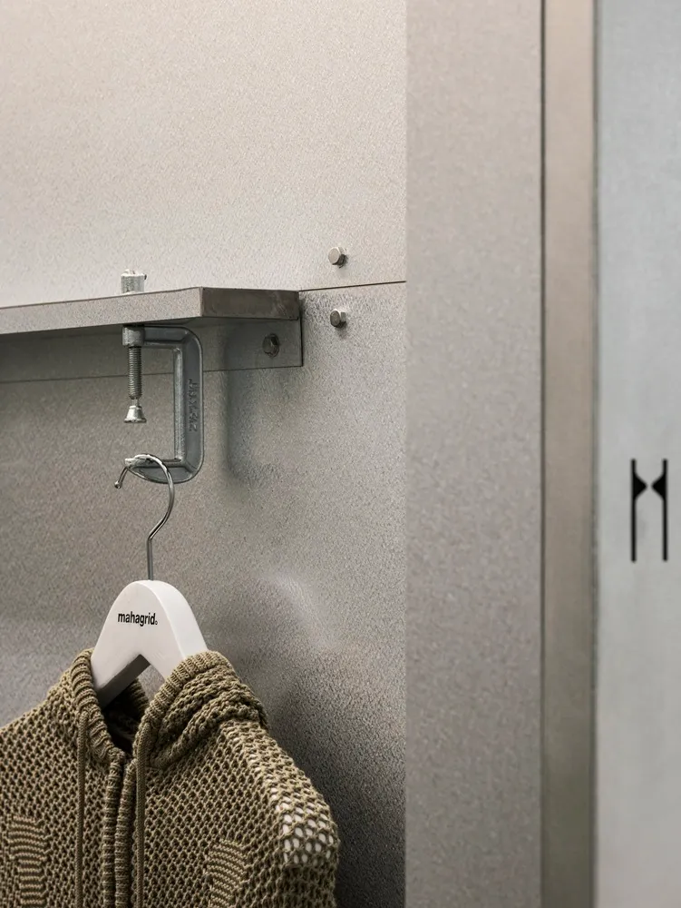 Clothing hooks hanging on a metal shelf in a storage area.