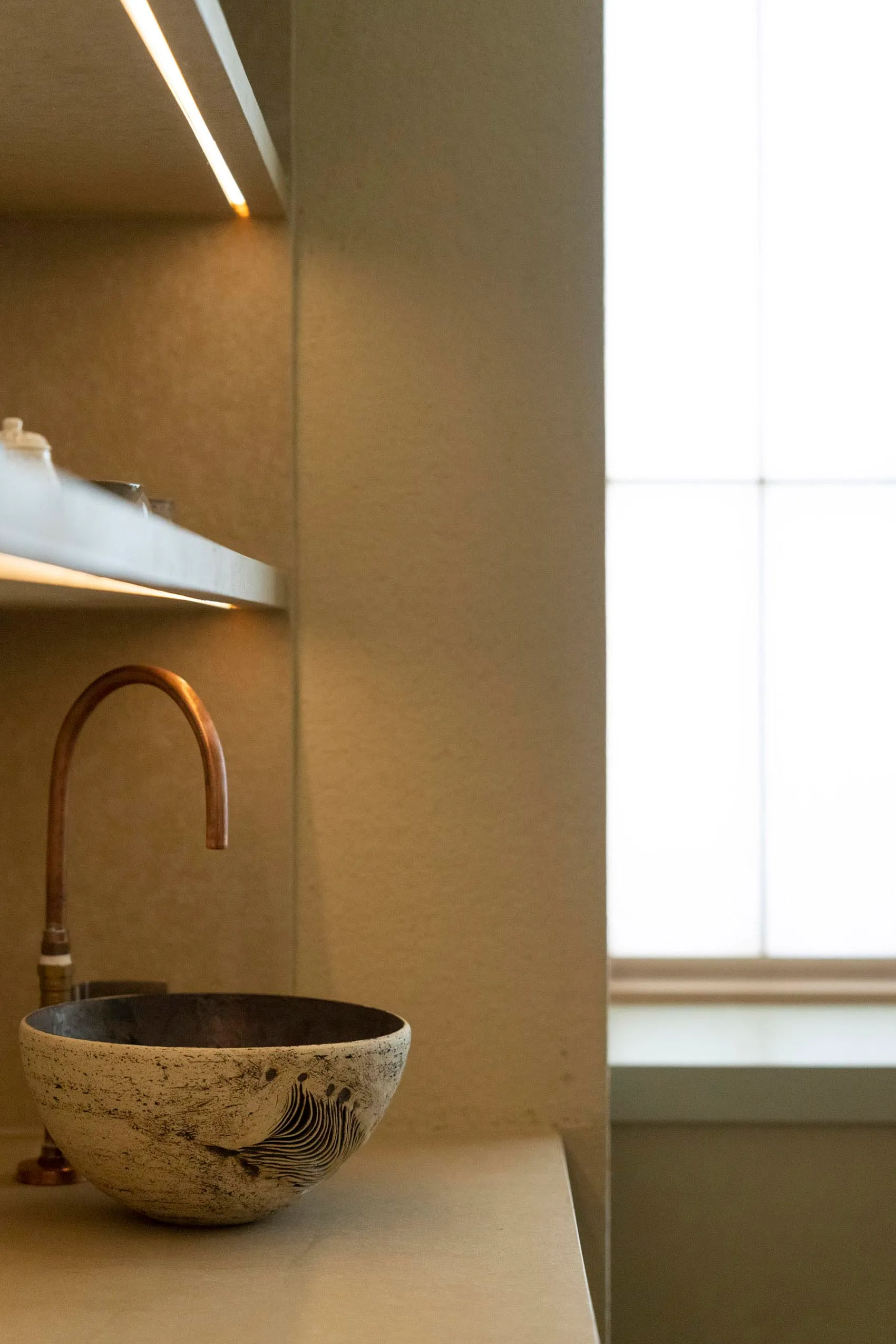 A minimalist bathroom featuring a concrete and marble sink with a curved faucet.