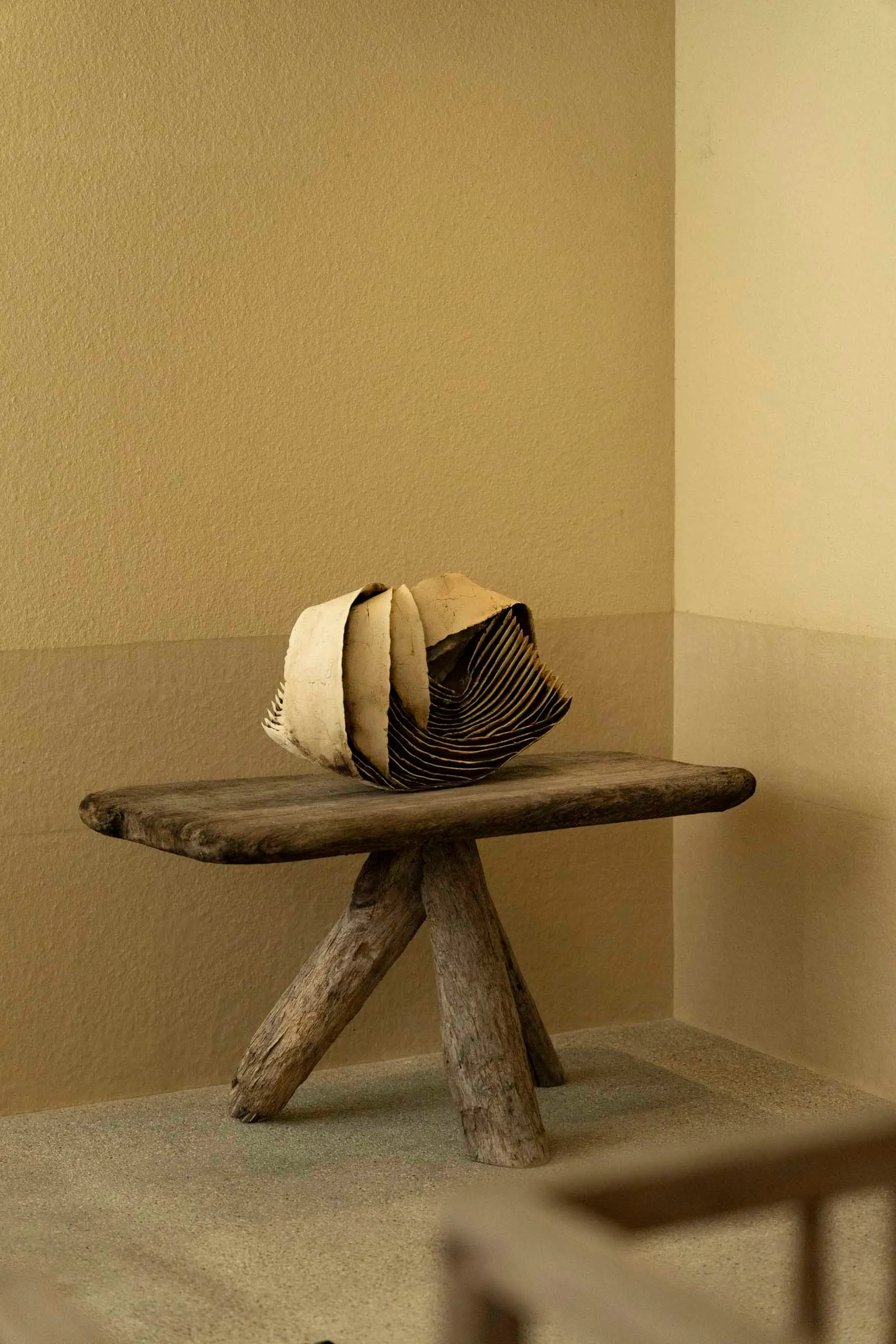 A minimalist wooden chair with a unique, folded seat design.