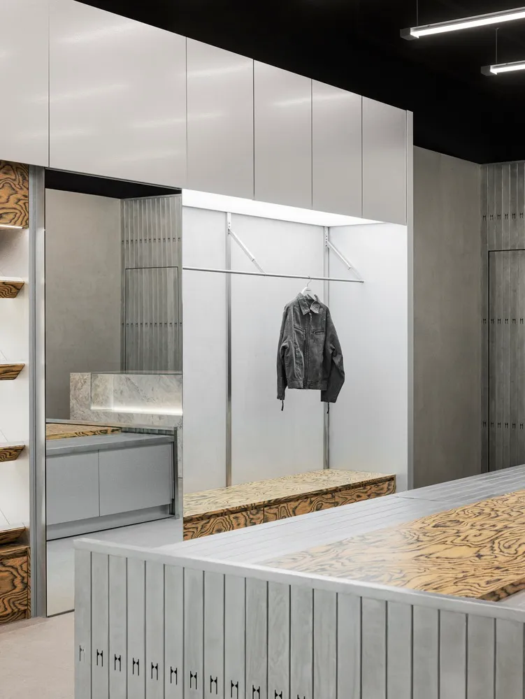 A modern clothing shop featuring minimalist design with metal, wood, and concrete materials.
