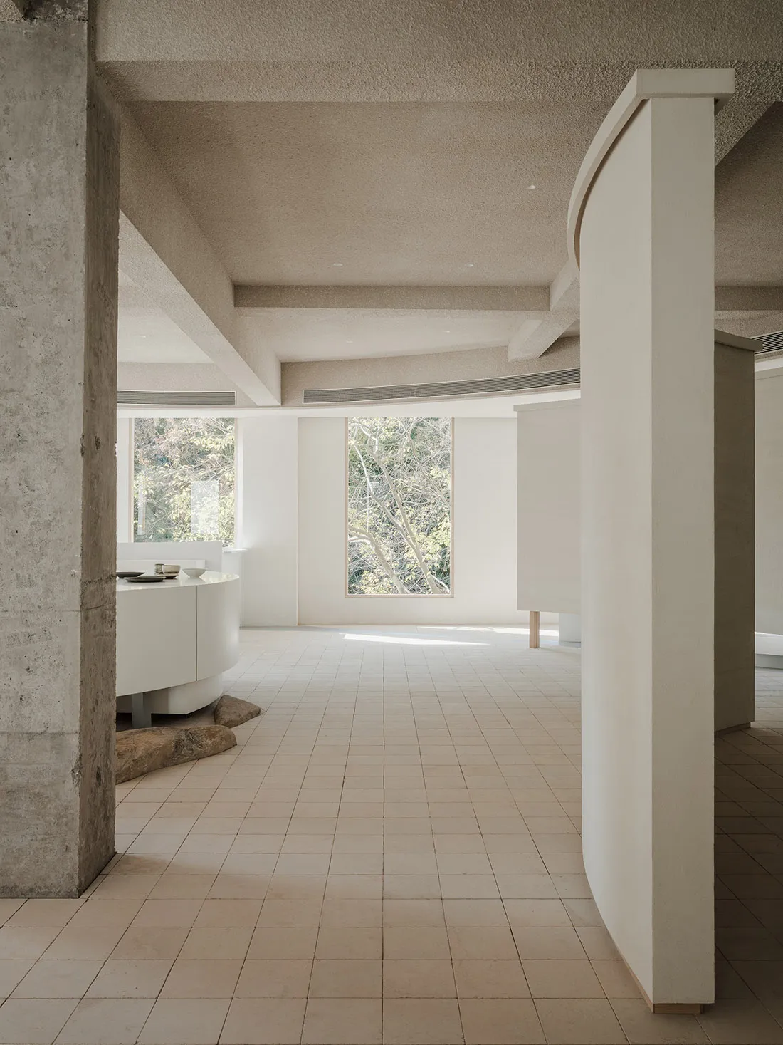 A modern living room with concrete walls and white tiled flooring.