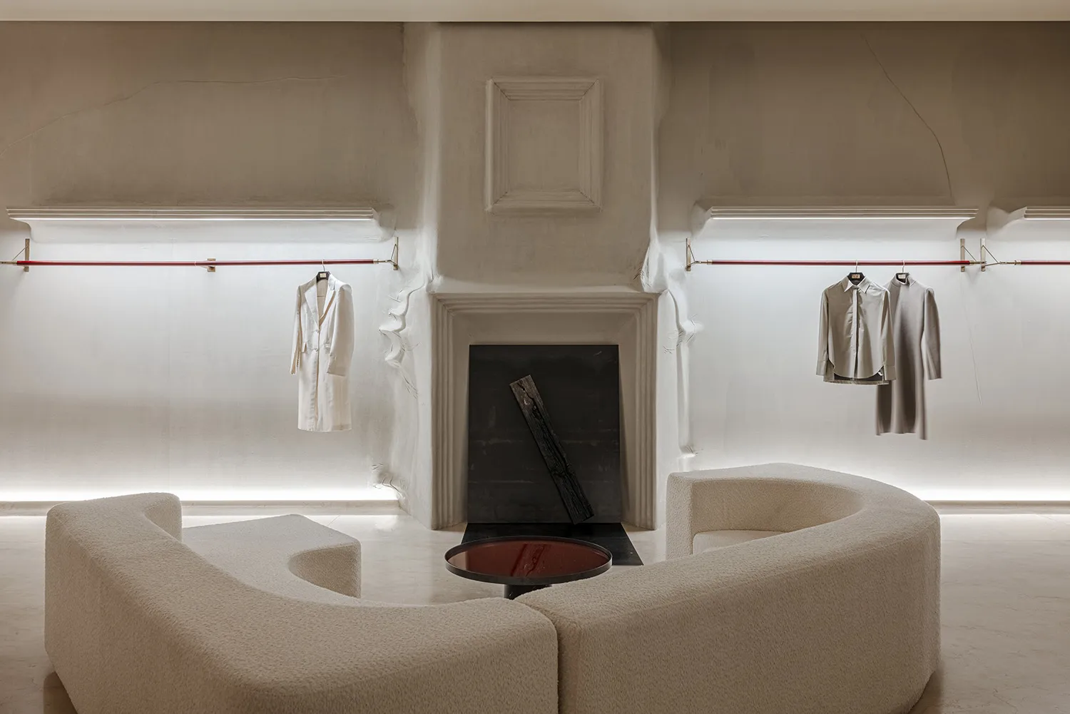 A minimalist retail store featuring a concrete interior with modern furniture and minimalist clothing hanging on the walls.