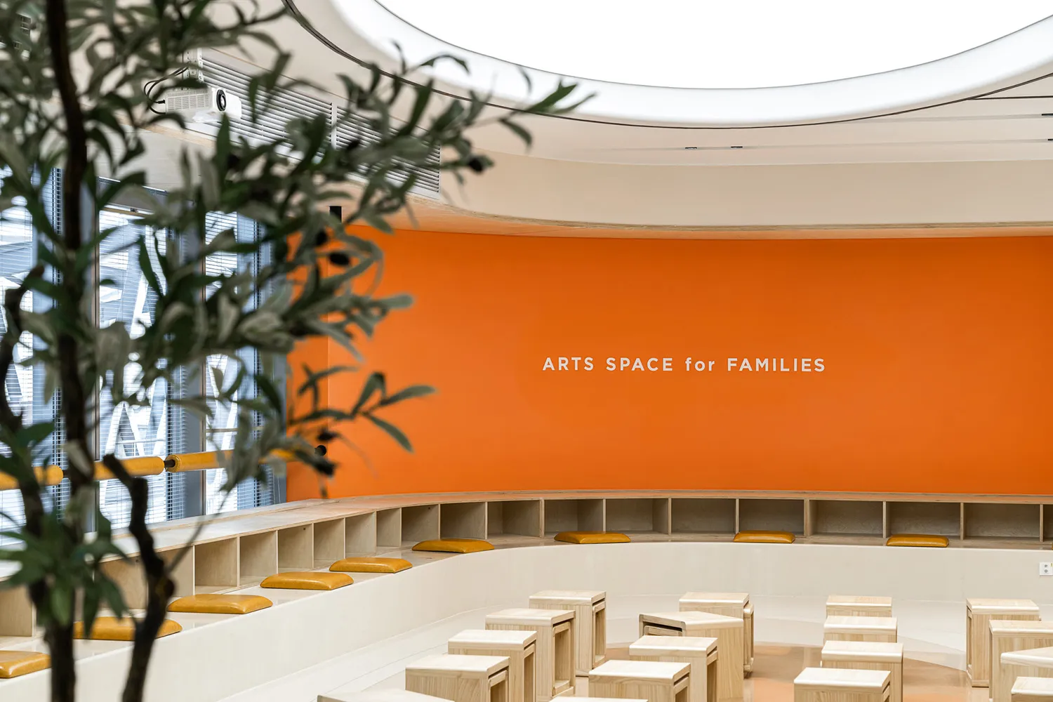 現代室內設計,橘色牆面印有「ARTS SPACE for FAMILIES」文字,並配置多種座位安排。