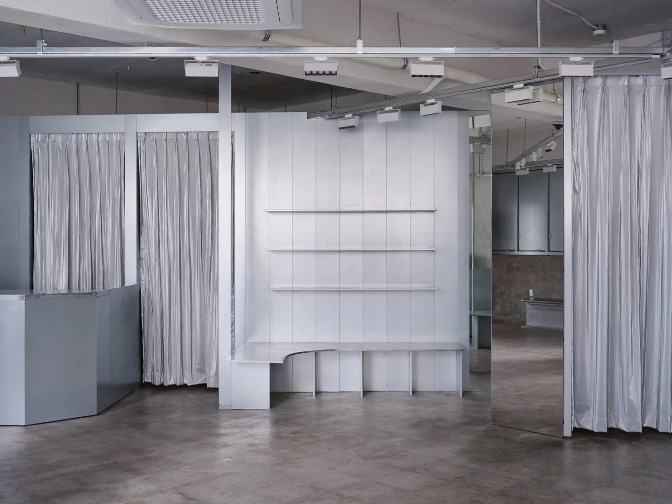 Minimalist interior of a retail shop featuring metal, glass, and mirrored surfaces.