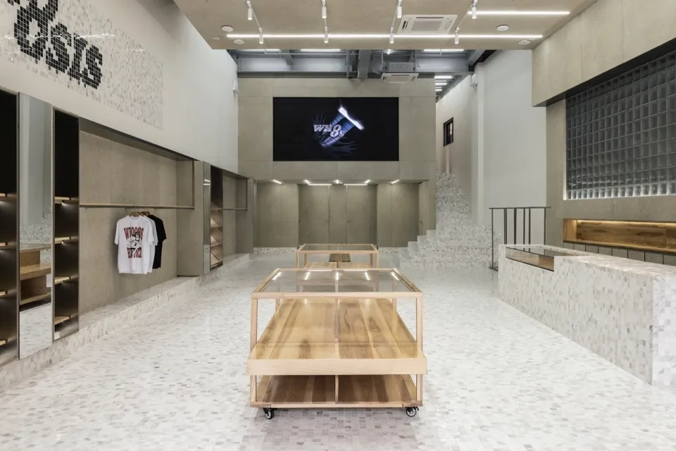 Modern retail storefront featuring wooden concrete and marble tables, with a digital display in the background.