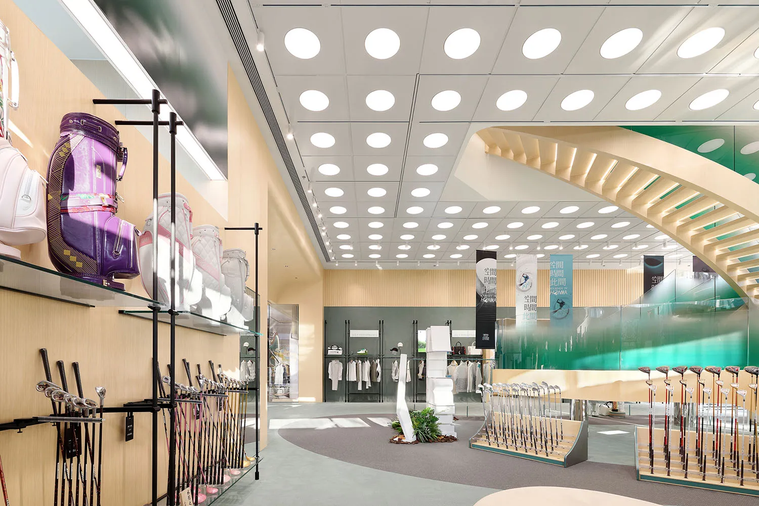 一間燈光明亮的零售店室內空間,採用玻璃與金屬材質,陳列高爾夫球袋、球桿及服飾。