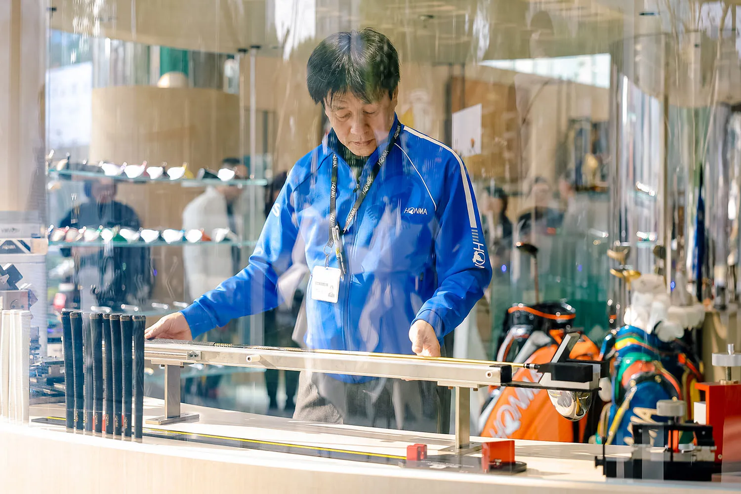 Man in a golf shop adjusting a display case using tools and equipment.