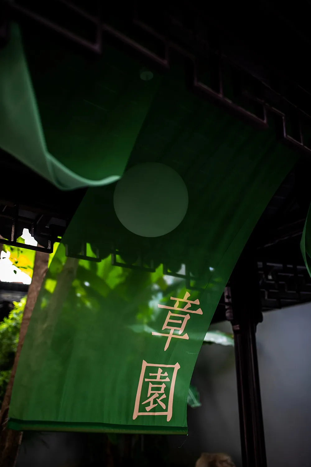 A green banner with Chinese characters hanging from a wooden beam