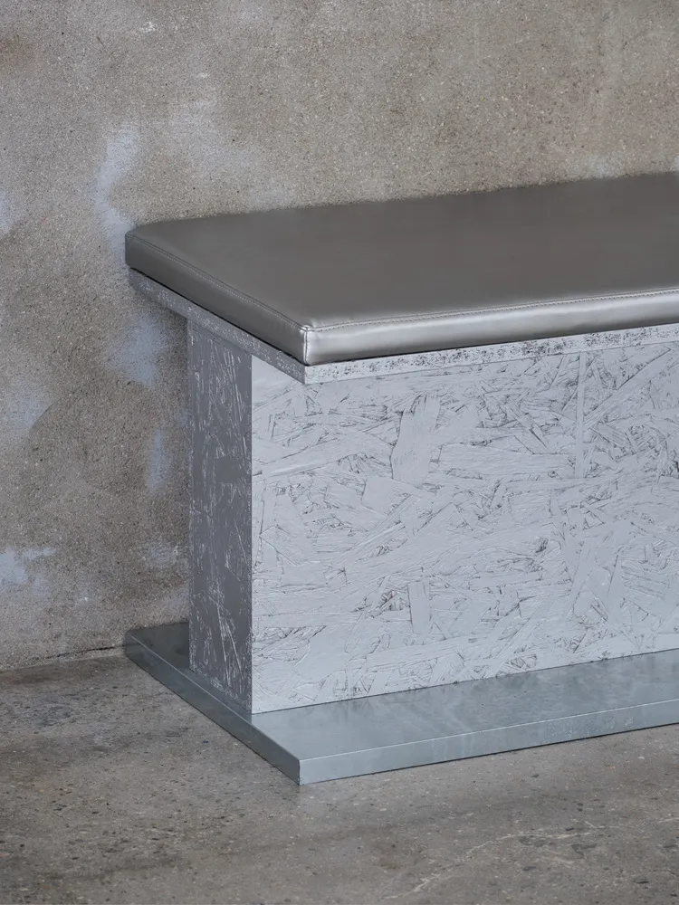 Industrial-style bench with a concrete base and gray cushioned seat.