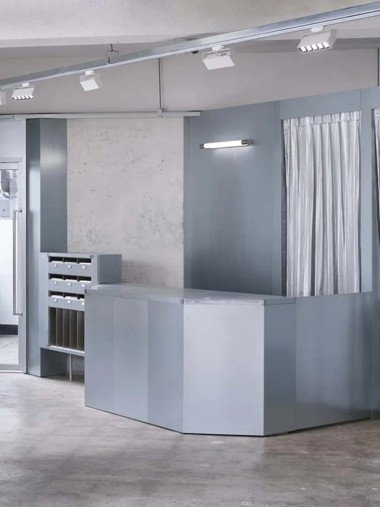A minimalist industrial-style lobby with metallic elements and concrete flooring.