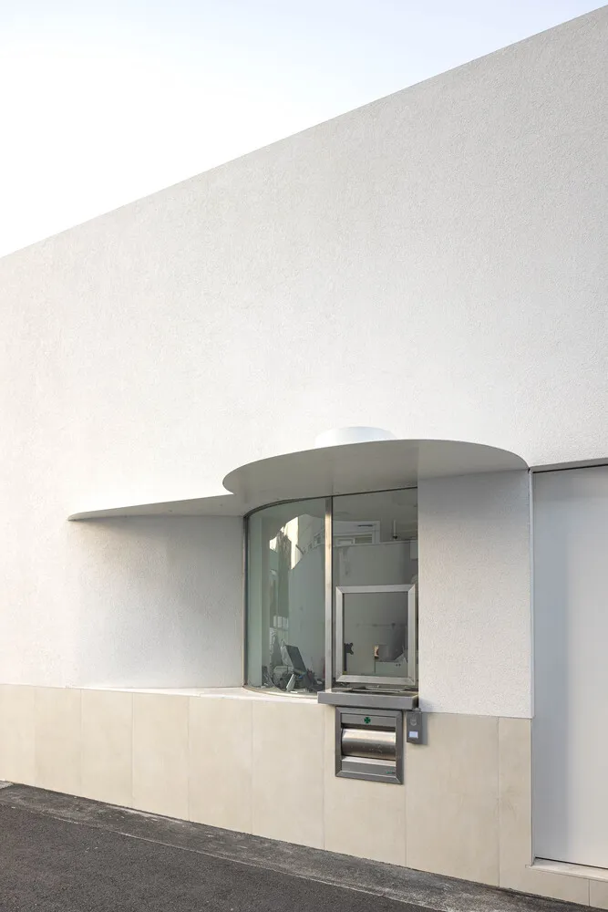 A minimalist, modern architectural exterior with white walls and a curved glass window.