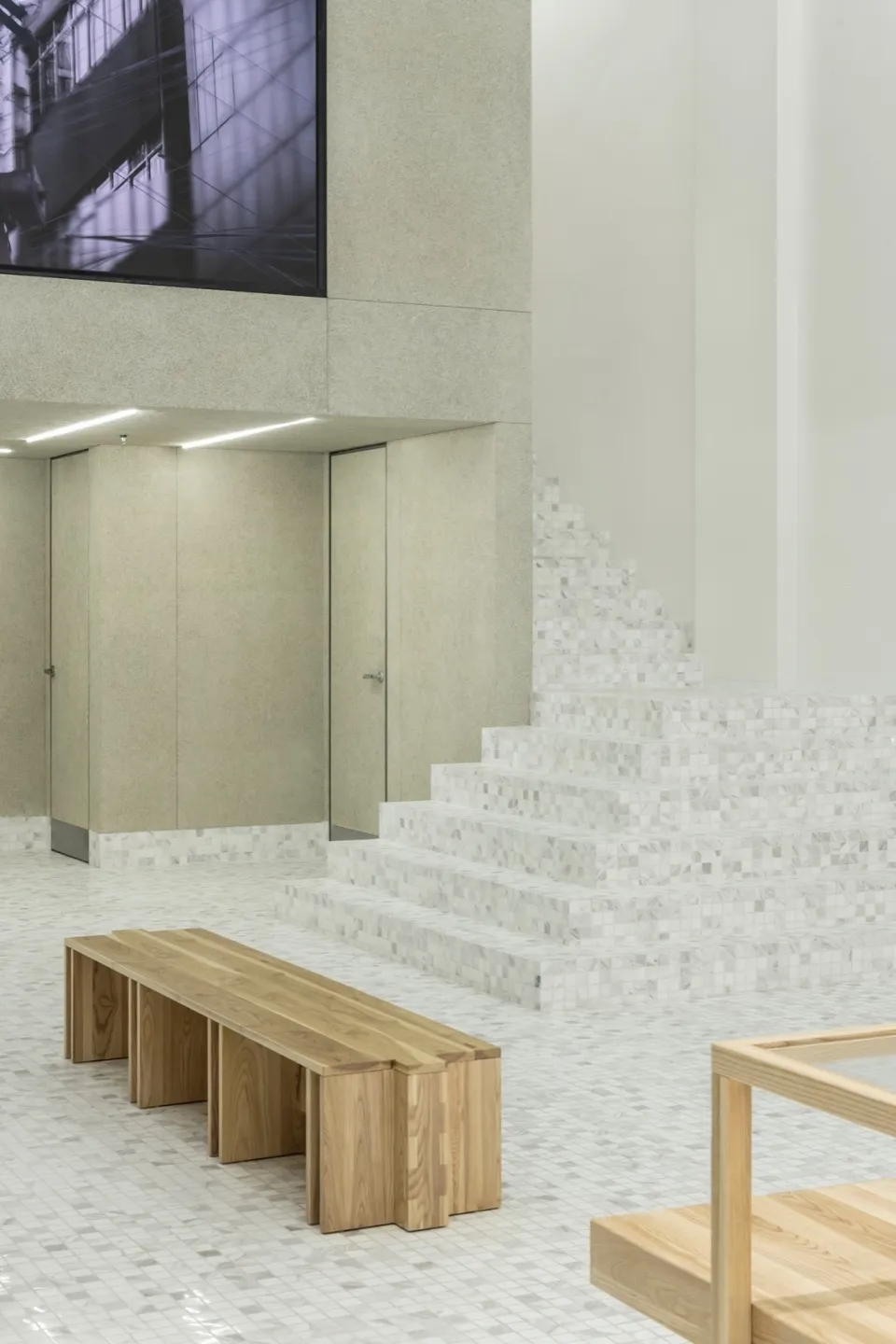 Industrial-style interior with concrete walls, marble stairs, and wooden bench and table