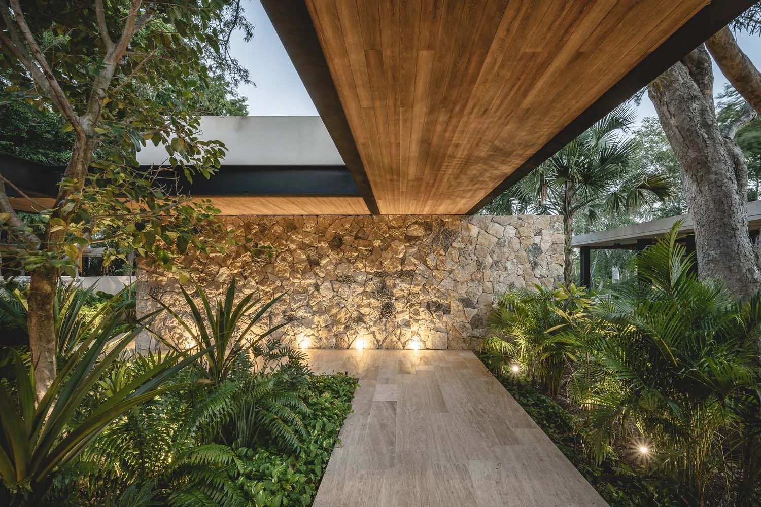 Modern patio with stone walls and floors surrounded by lush greenery and trees
