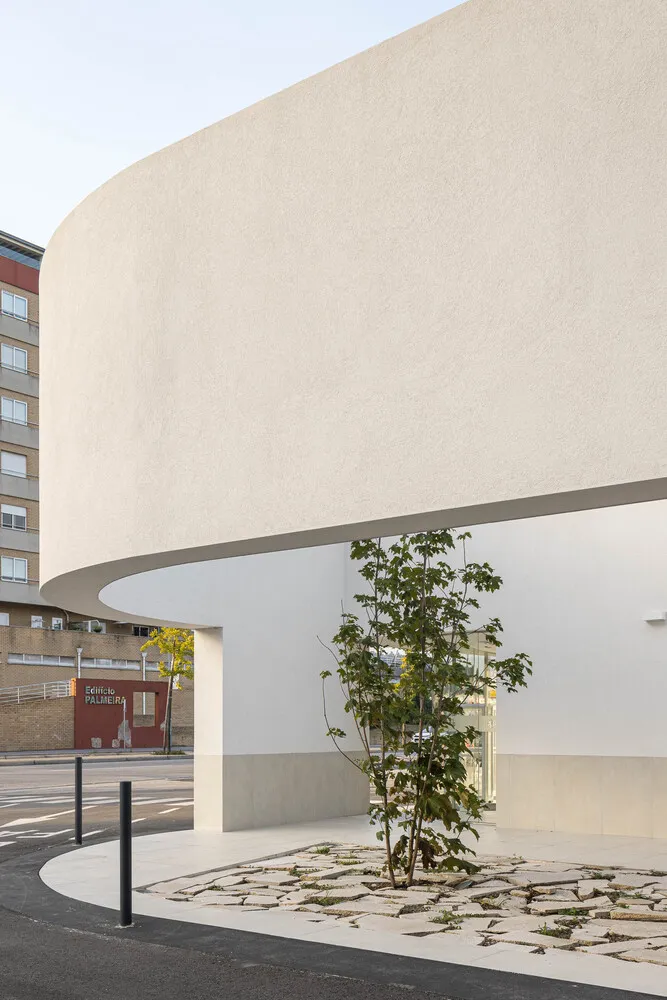 A modern urban space featuring concrete elements with a tree and mosaic tile entryway.