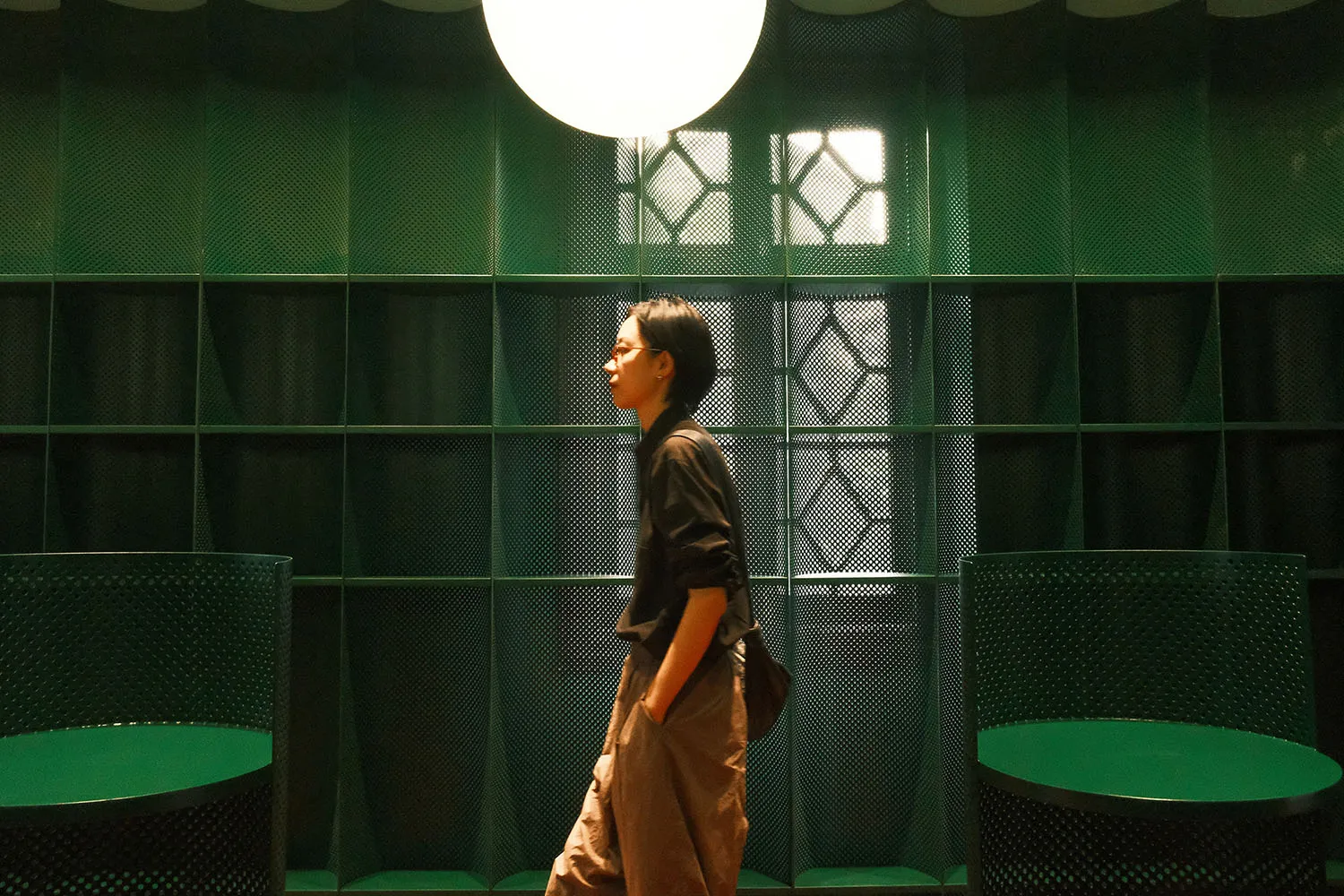 A person walking in a modern interior space with textured green walls
