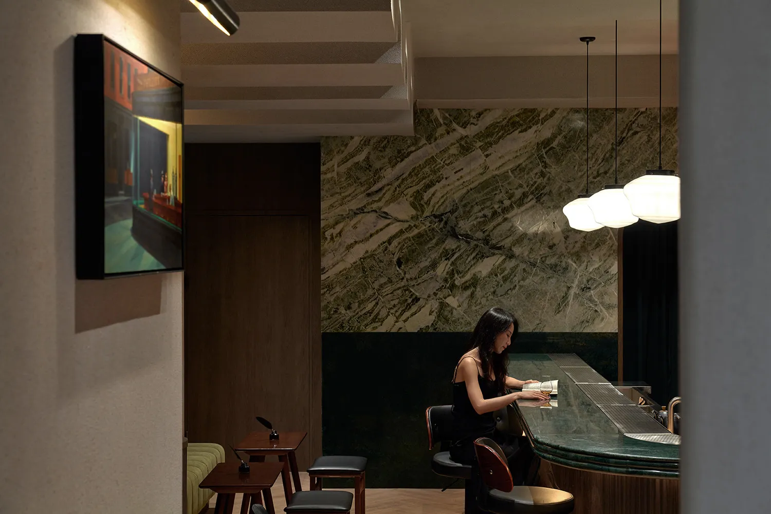 A modern bar with black marble countertops and black stools.