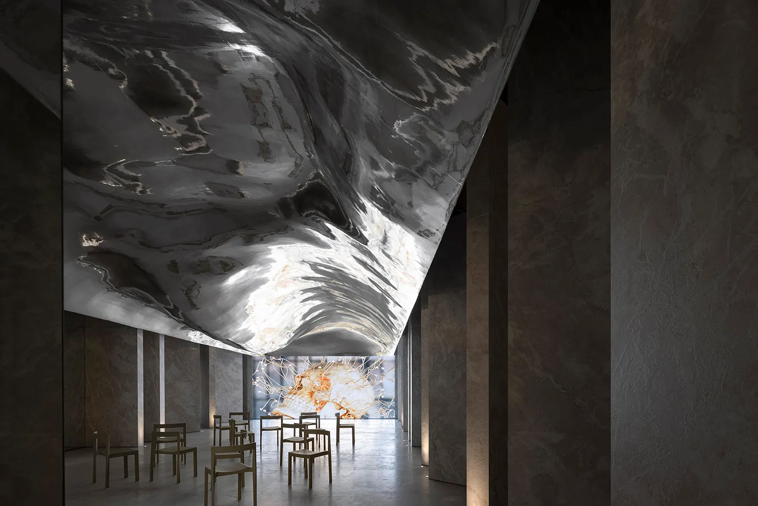 An interior space featuring a large, reflective black metal structure and modern furniture.