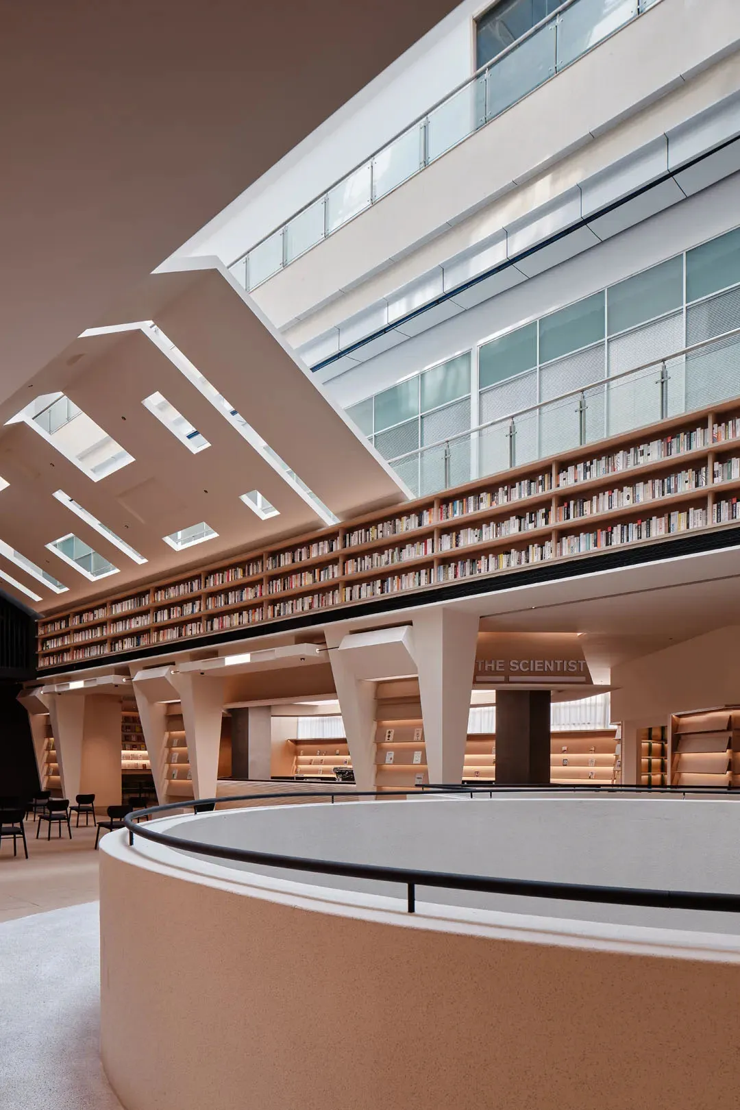 寬敞的現代學術圖書館室內,配有混凝土書架與大型天窗。