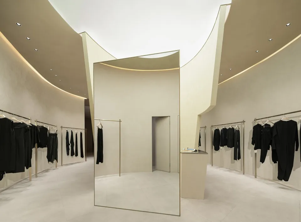 Minimalist fashion retail store with white reflective surfaces and neutral tones