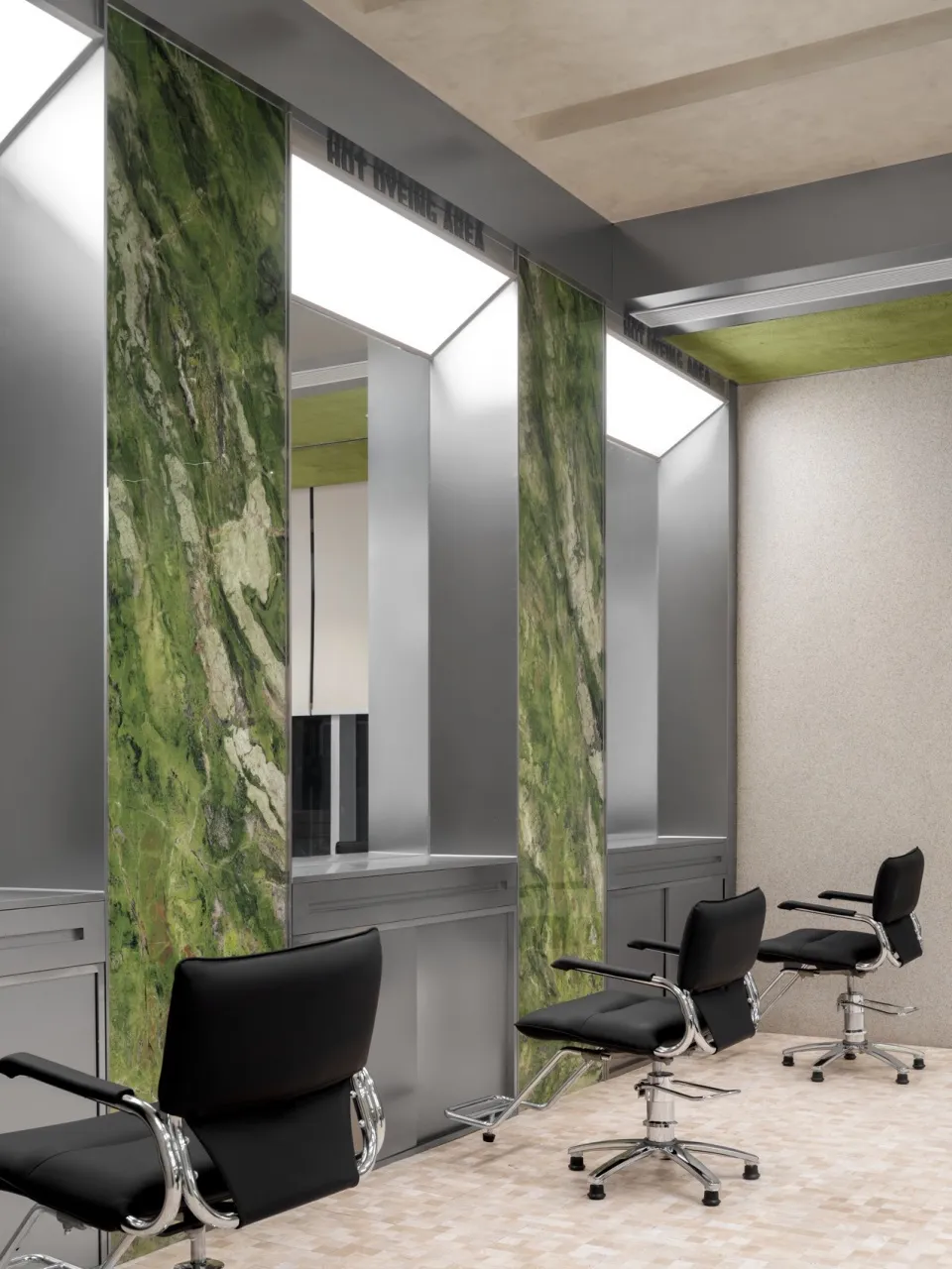 A hair salon with black chairs and green marble walls.