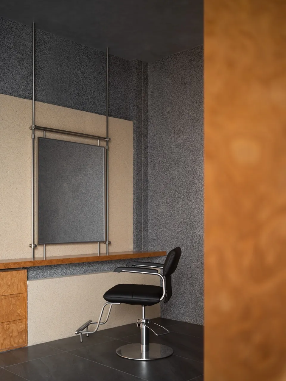 A stylish modern hair salon interior featuring a black leather chair, minimalistic design and wooden accents.