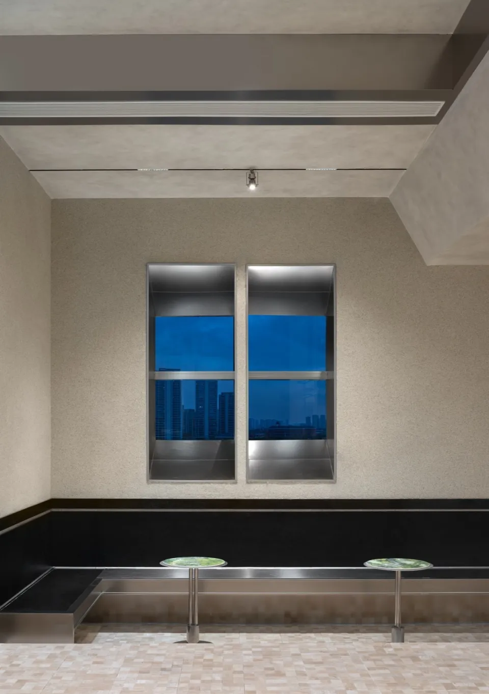 Modern lounge area with glass walls and concrete seating.