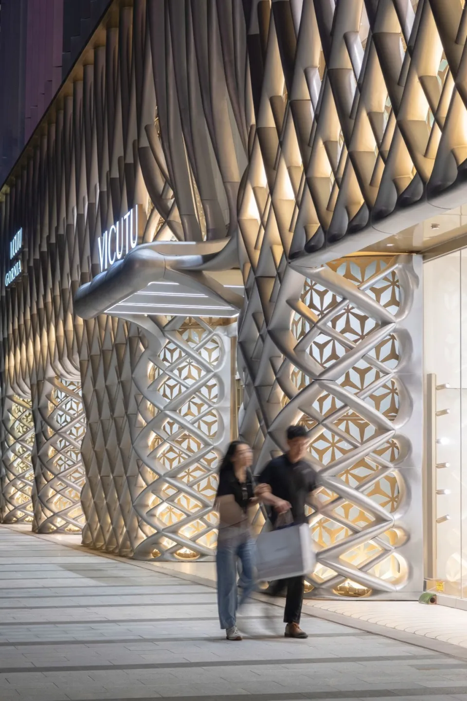 A modern storefront at night with a metallic facade and illuminated details.