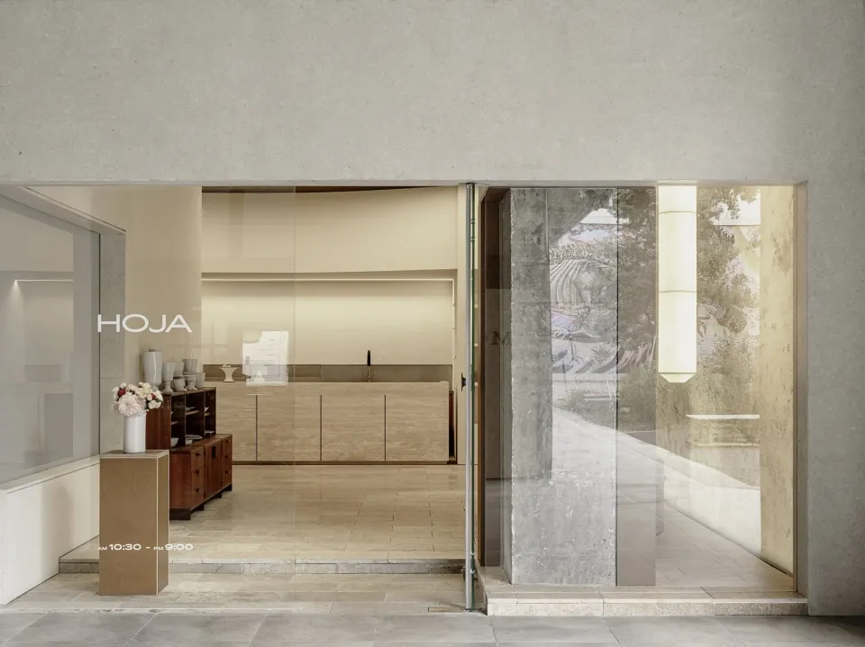 Interior of a modern coffee shop, featuring concrete walls and large glass windows.