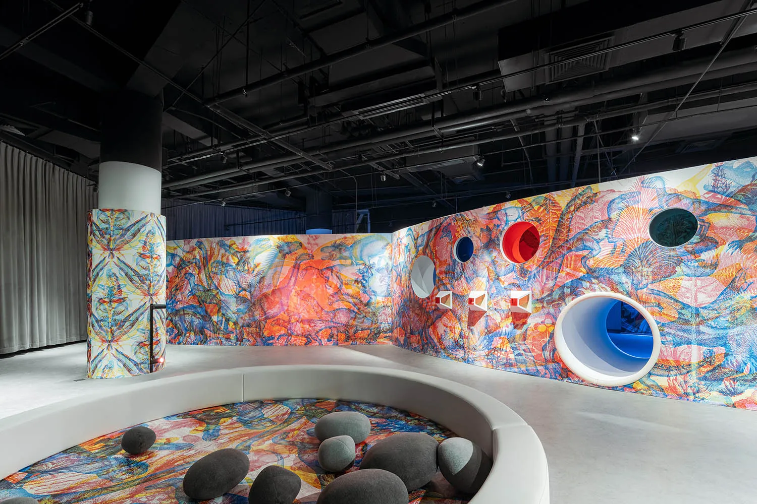 A modern installation featuring colorful painted sculptures and a circular seating area with stones.