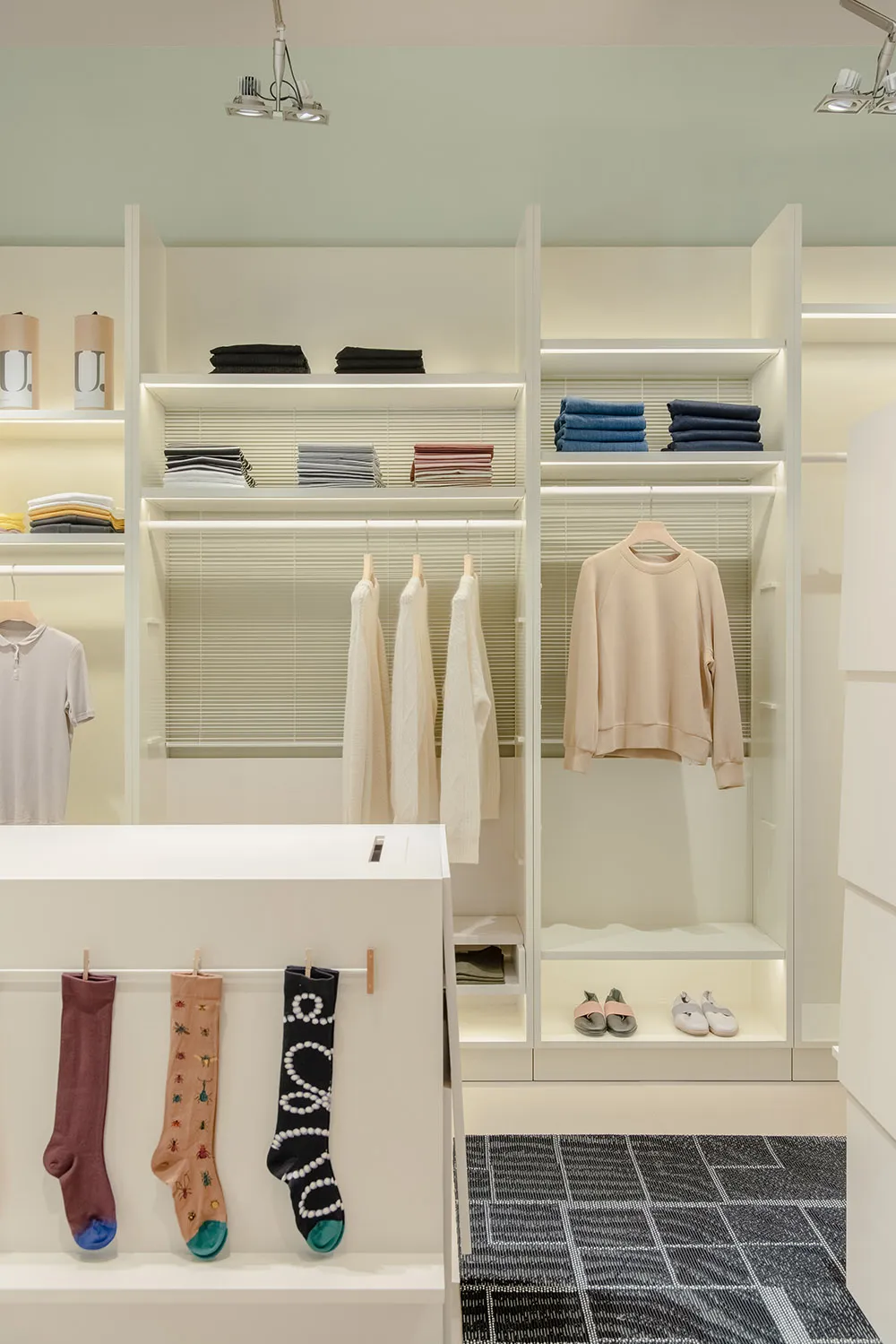 A stylish and organized minimalist fashion closet with white shelves and steel hangers.
