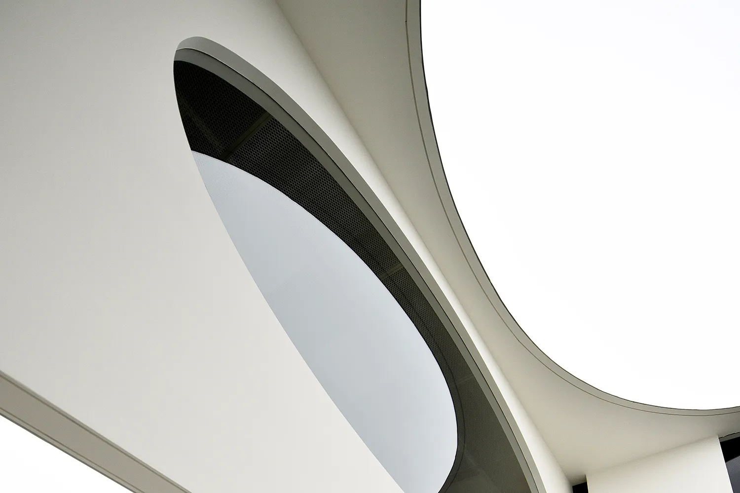 Modern architecture design featuring a sleek concrete ceiling with a large circular opening.