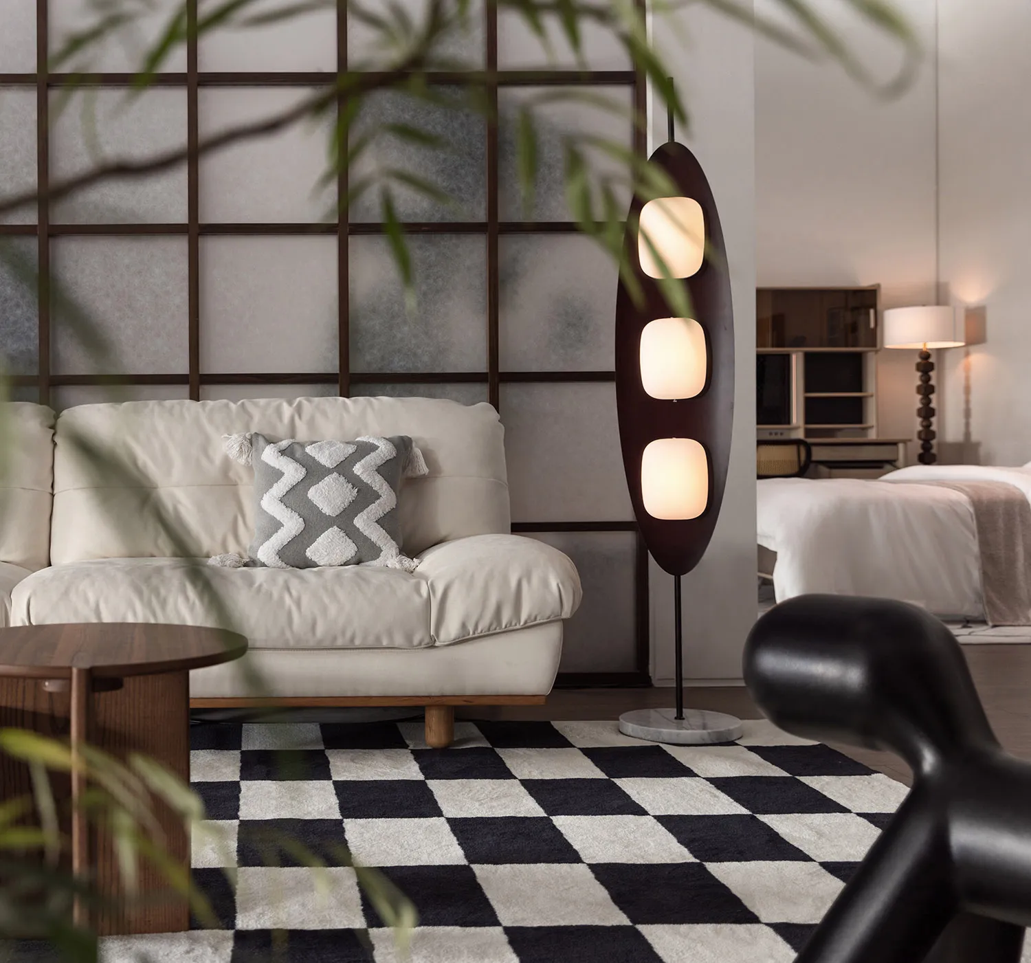 A modern living room featuring a white leather sofa with a geometric gray cushion, a black marble floor lamp, a checkered bla