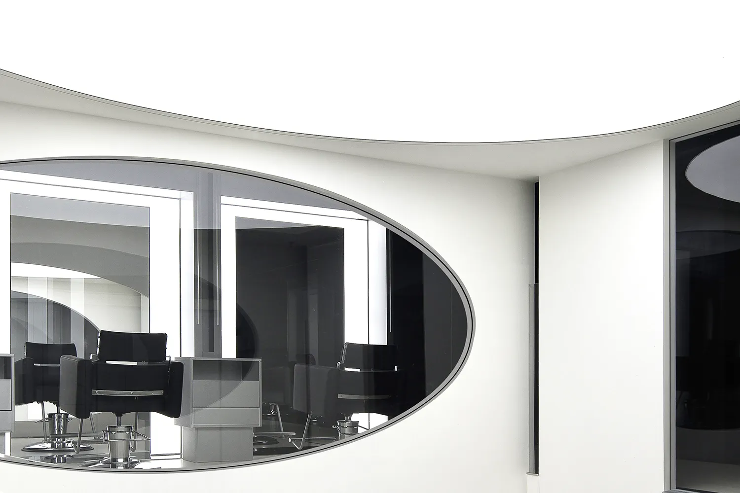 Modern, minimalist salon interior with sleek black chairs and white walls.