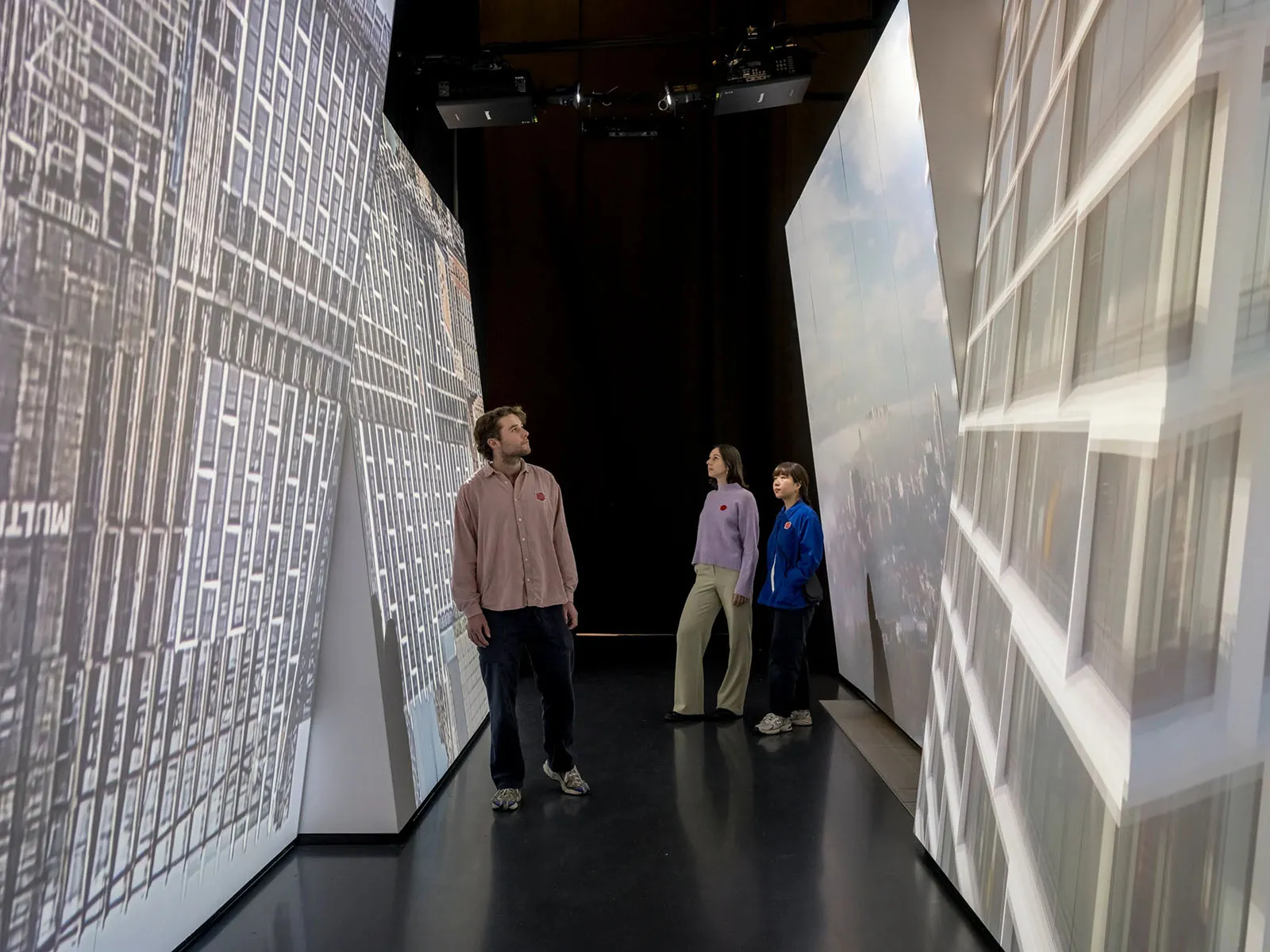 三位人士站在博物館展區,展示建築物的3D立體視圖。