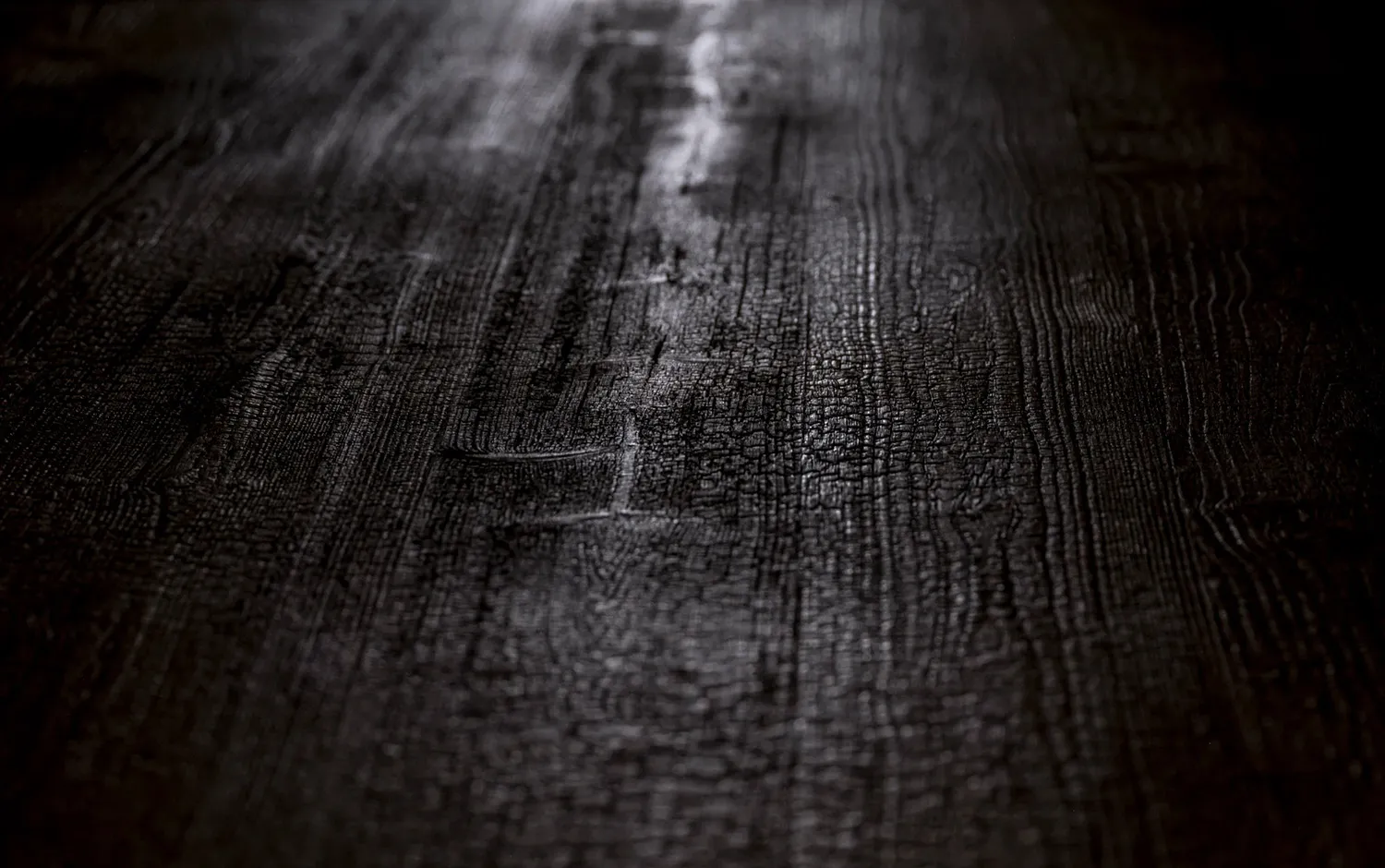 A close-up view of a dark wooden floor texture, showcasing the natural grain and rustic appearance.