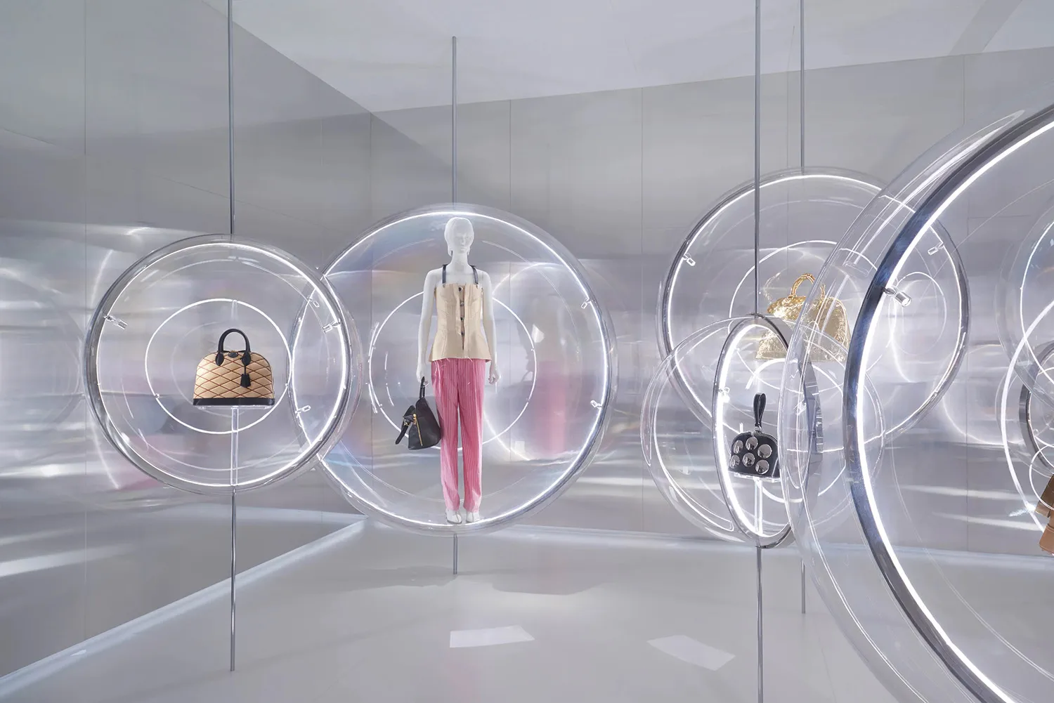 A minimalist retail display featuring clear plastic spheres containing fashion accessories and clothing.