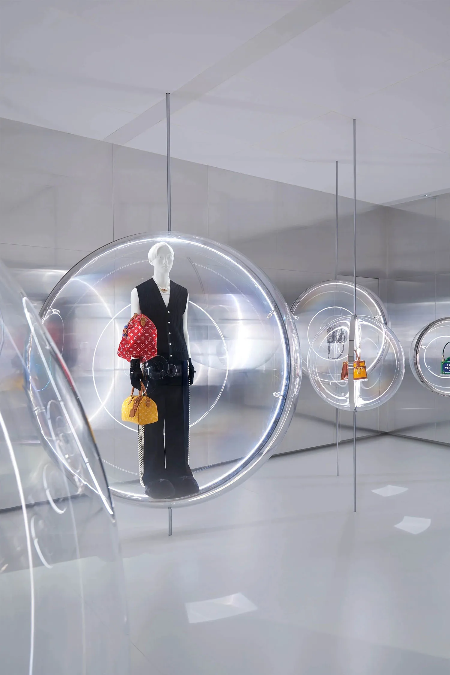 A modern retail display featuring a mannequin dressed in black and yellow clothing, holding a red bag, suspended inside a tra