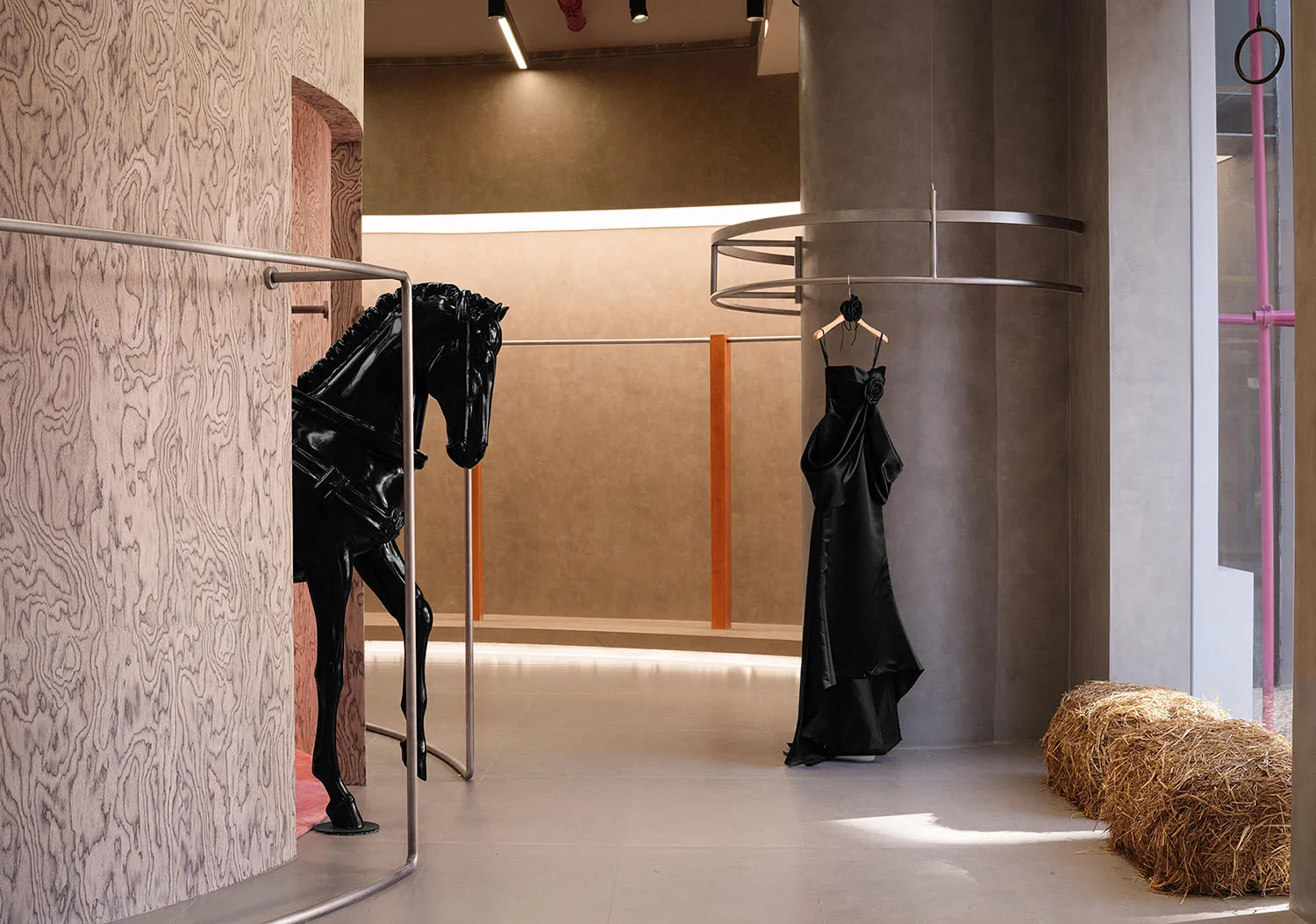 優雅的時尚精品店室內,展示一尊黑色馬匹雕像、一件黑色禮服懸掛於圓形衣架上,以及一捆