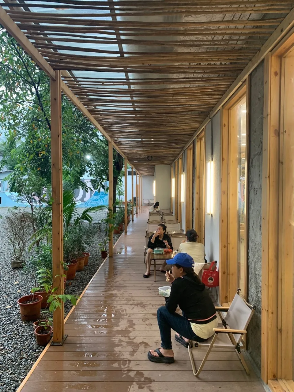 Cafe terrace with wooden ceiling, industrial design, and potted plants.