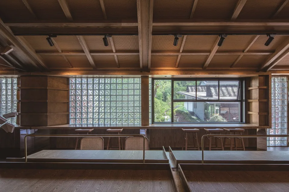 Industrial-style restaurant interior with wooden materials and large windows.