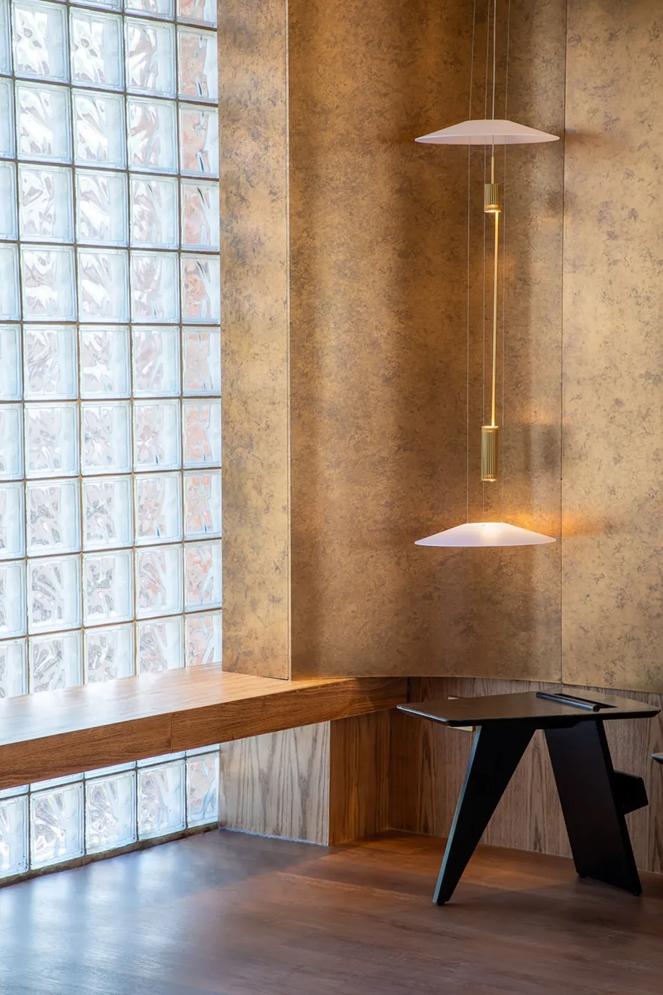 A modern coffee shop interior featuring wooden seating and glass blocks in the window.