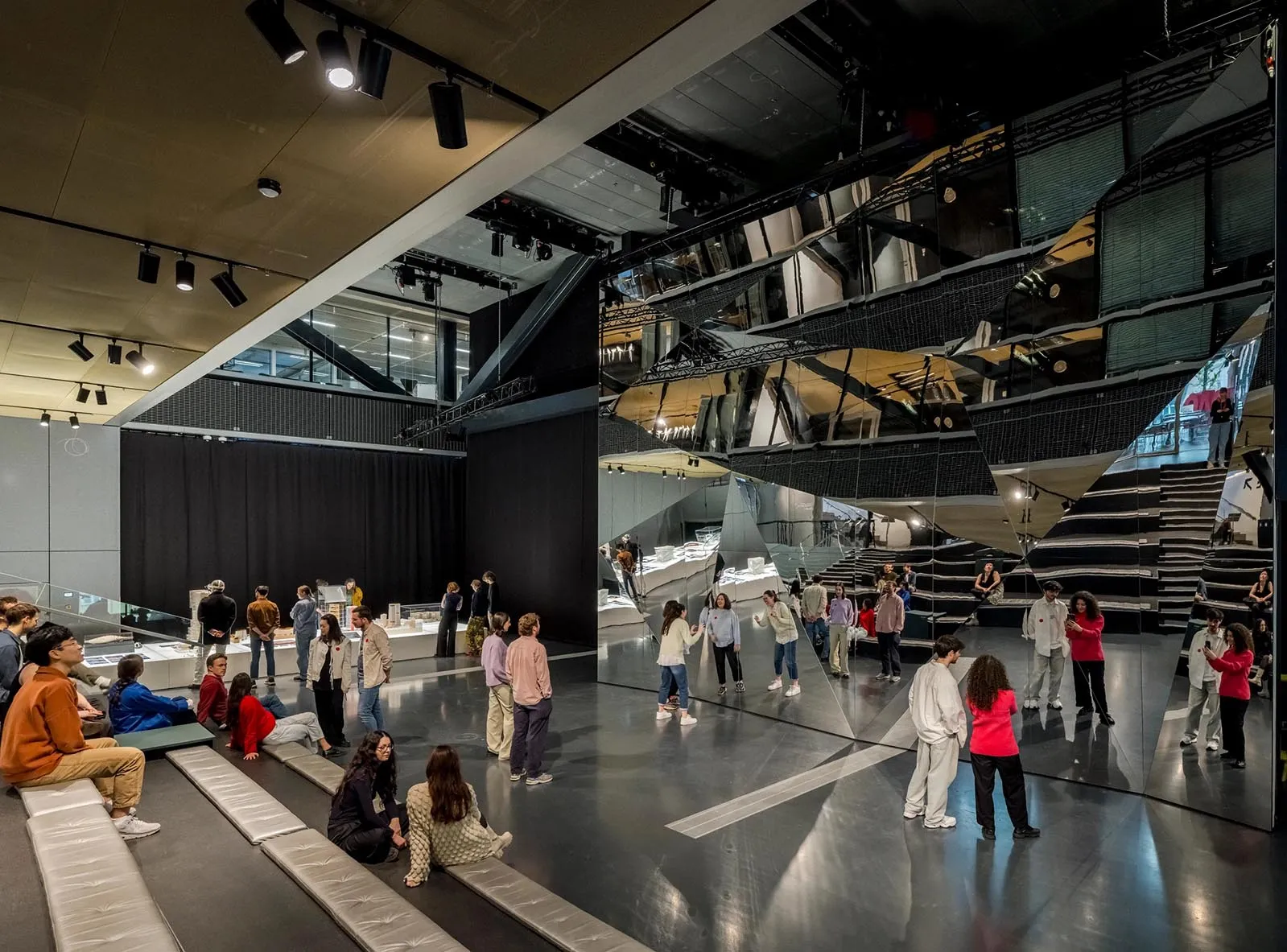 Visitors exploring a contemporary museum exhibition with reflective surfaces and geometric shapes.