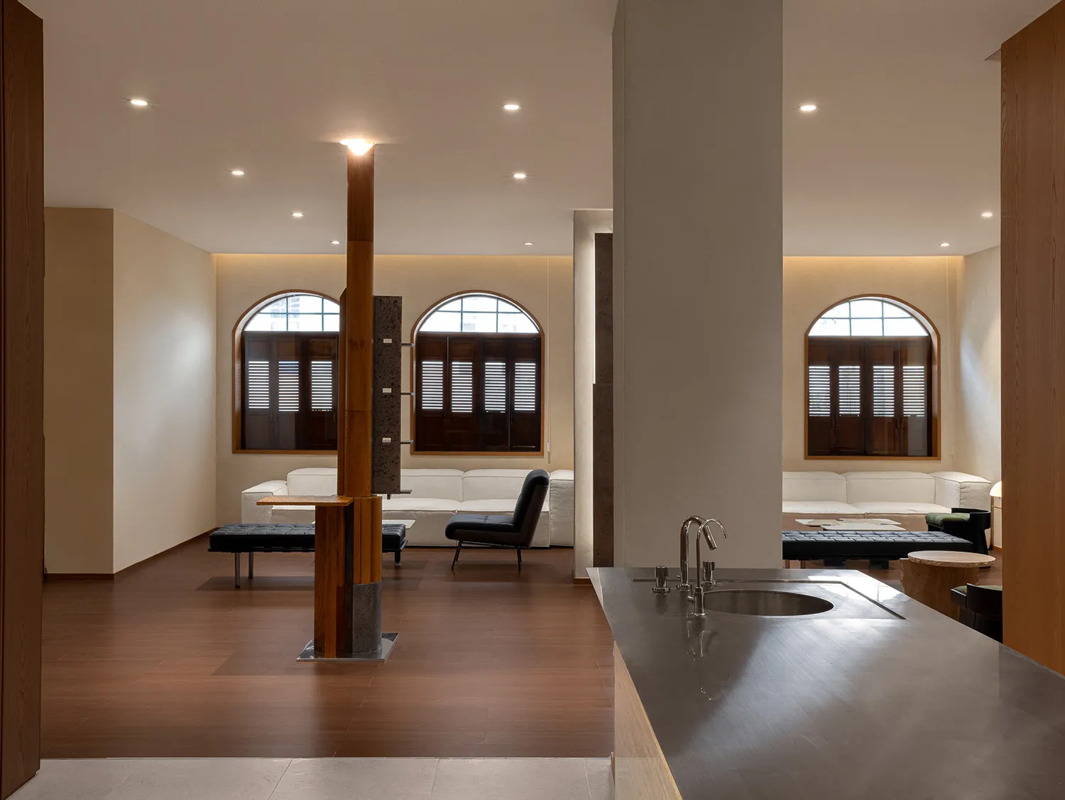 Modern minimalist living room with wooden floors, concrete accents, and large windows.