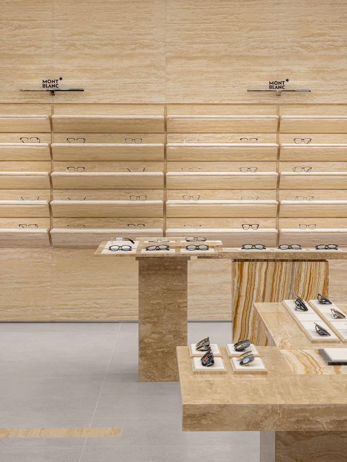 Modern glasses store with marble interior and shelves displaying various eyewear products.