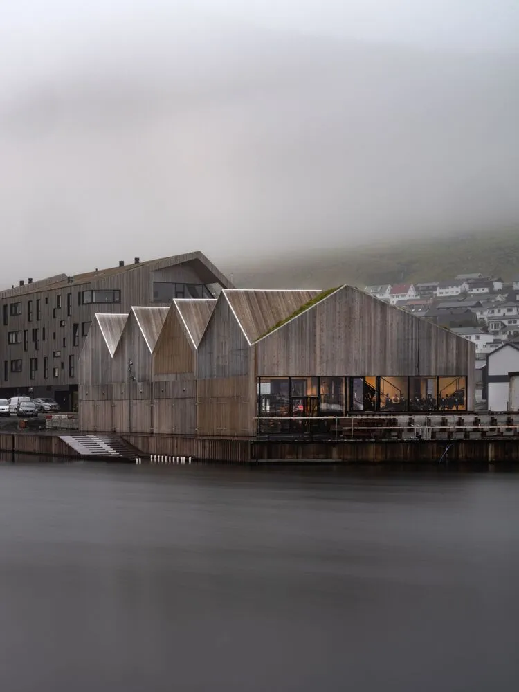 A modern industrial wooden building with a sloped roof and large glass windows.