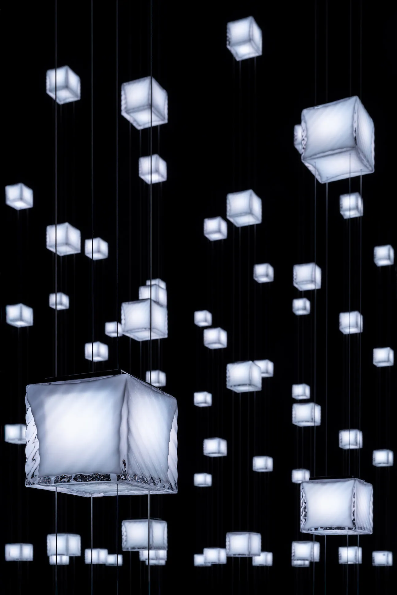 Modern lighting design featuring illuminated cubes hanging from black wires.