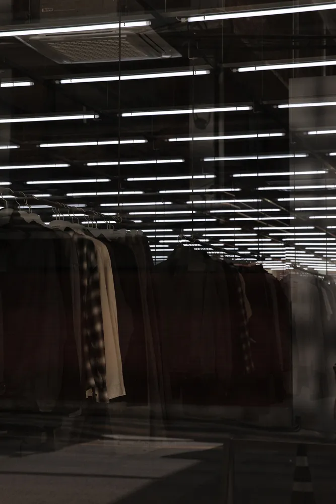 Clothing items hanging on racks in a glass-walled retail display